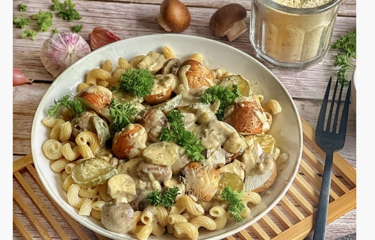 Vegane Nudeln mit Champignons und Gurken auf einem Teller.