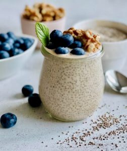 Veganer Chia-Pudding mit Beeren und Nüssen in einem Glas.