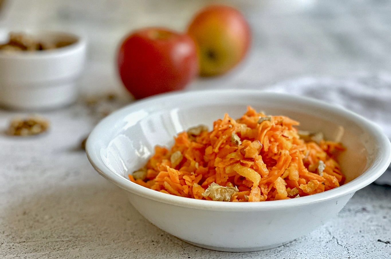 Fruchtiger Karottensalat mit Apfel und Walnüssen in einer Schüssel.