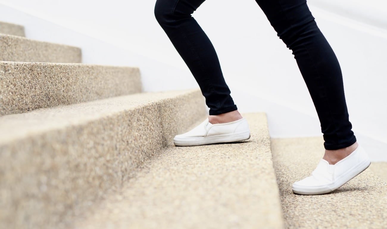 Frauenbeine, die eine Treppe hochgehen.