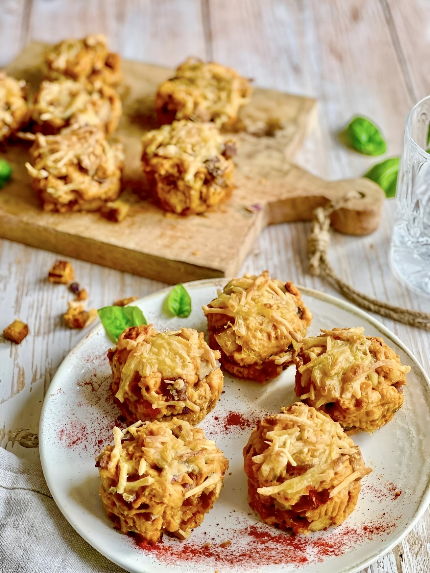 Vegane herzhafte Muffins mit Käsekruse auf einem Teller und einem Brett.