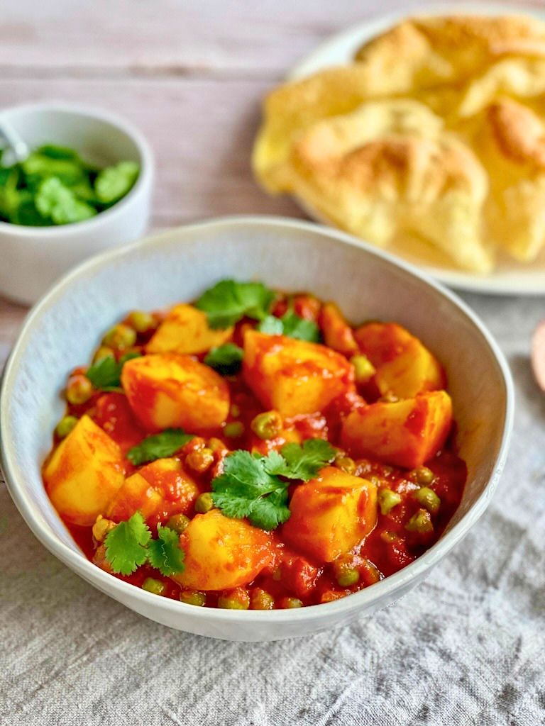 Aloo Matar: Ein veganes indisches Curry mit Kartoffeln und Erbsen auf einem Teller.