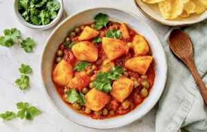 Veganes Aloo Matar: Ein herzhaftes indisches Curry mit Kartoffeln und Erbsen auf einem Teller.