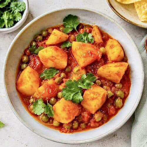 Veganes Aloo Matar: Ein herzhaftes indisches Curry mit Kartoffeln und Erbsen auf einem Teller.