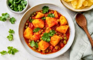 Aloo Matar: Ein veganes herzhaftes indisches Curry mit Kartoffeln und Erbsen auf einem Teller.