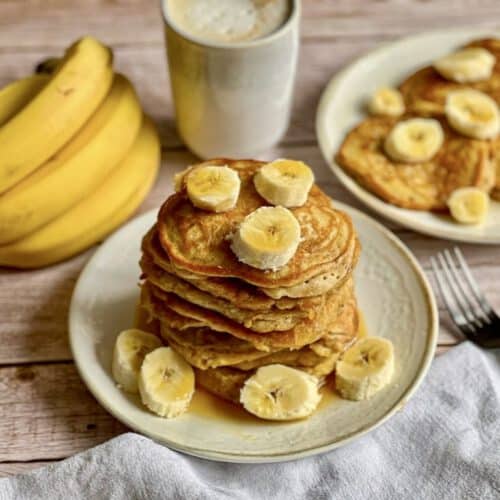 Vegane Bananen-Pancakes mit Ahornsirup gestapelt auf einem Teller.