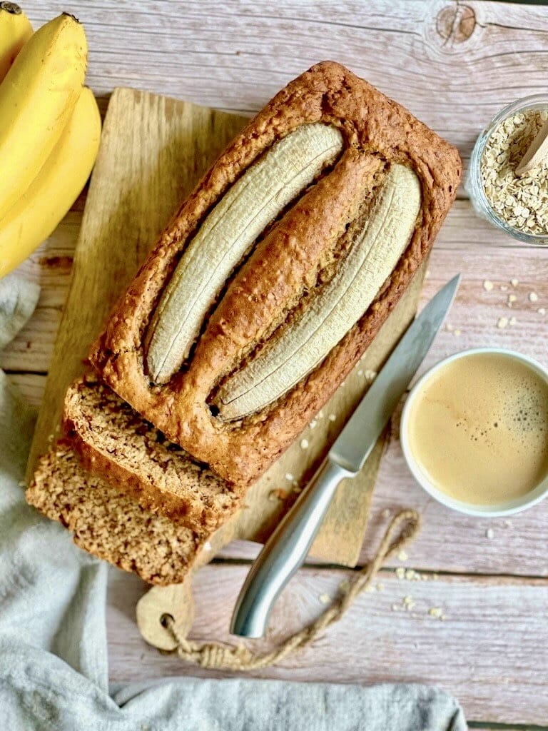 Veganes Bananenbrot mit Haferflocken auf einem Holzbrett.