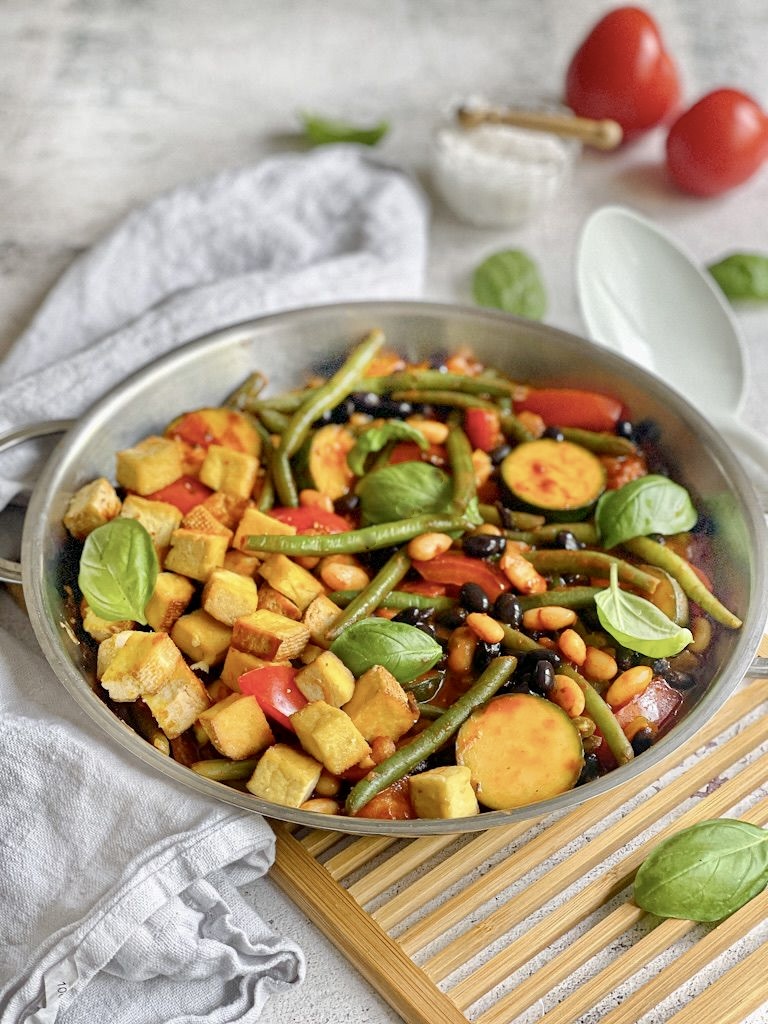 Deftige vegane Bohnenpfanne mit Räuchertofu, Tomaten und Basilikum.