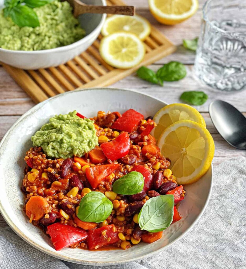 Veganes Chili sin Carne mit Buchweizen und Guacamole auf einem Teller.