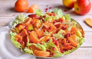 Chinakohlsalat mit Mandarinen, Äpfeln, Karotten und Granatapfelkernen in einer Schüssel