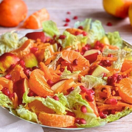 Chinakohlsalat mit Mandarinen, Äpfeln, Karotten und Granatapfelkernen in einer Schüssel