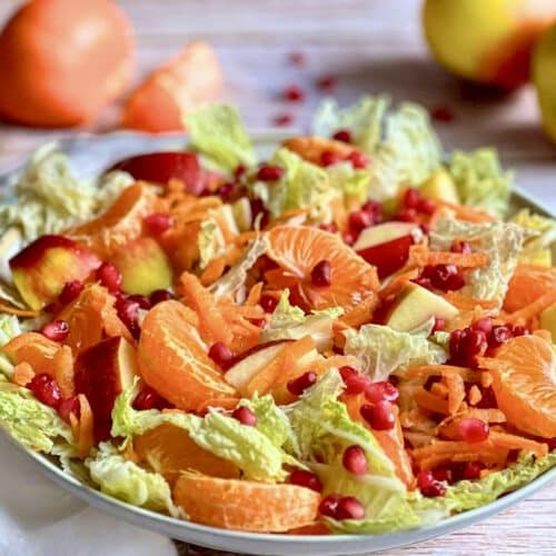 Chinakohlsalat mit Mandarinen, Äpfeln, Karotten und Granatapfelkernen in einer Schüssel