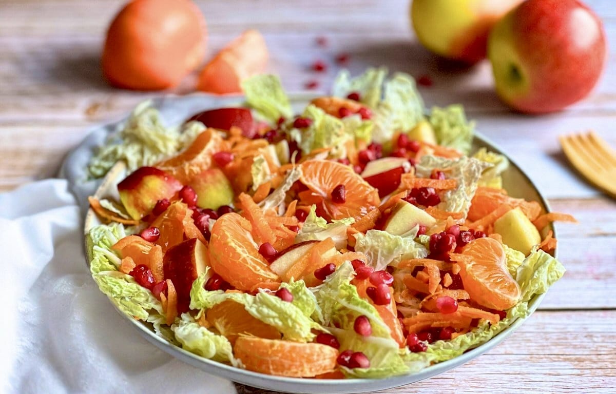 Chinakohlsalat mit Mandarinen, Äpfeln, Karotten und Granatapfelkernen in einer Schüssel