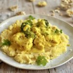 Kartoffelstampf mit Blumenkohl und Brokkoli in einer cremigen Cashewsoße auf einem Teller.