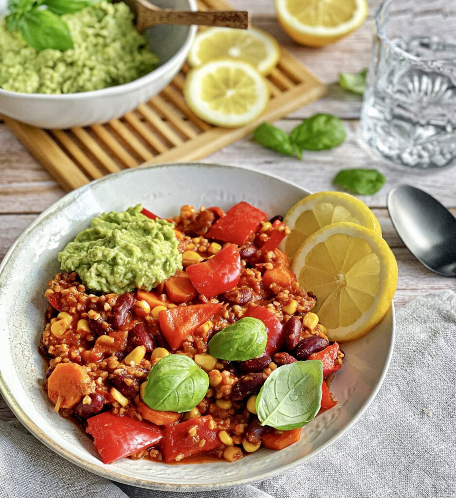 Veganes Chili sin Carne mit Buchweizen und Guacamole auf einem Teller.