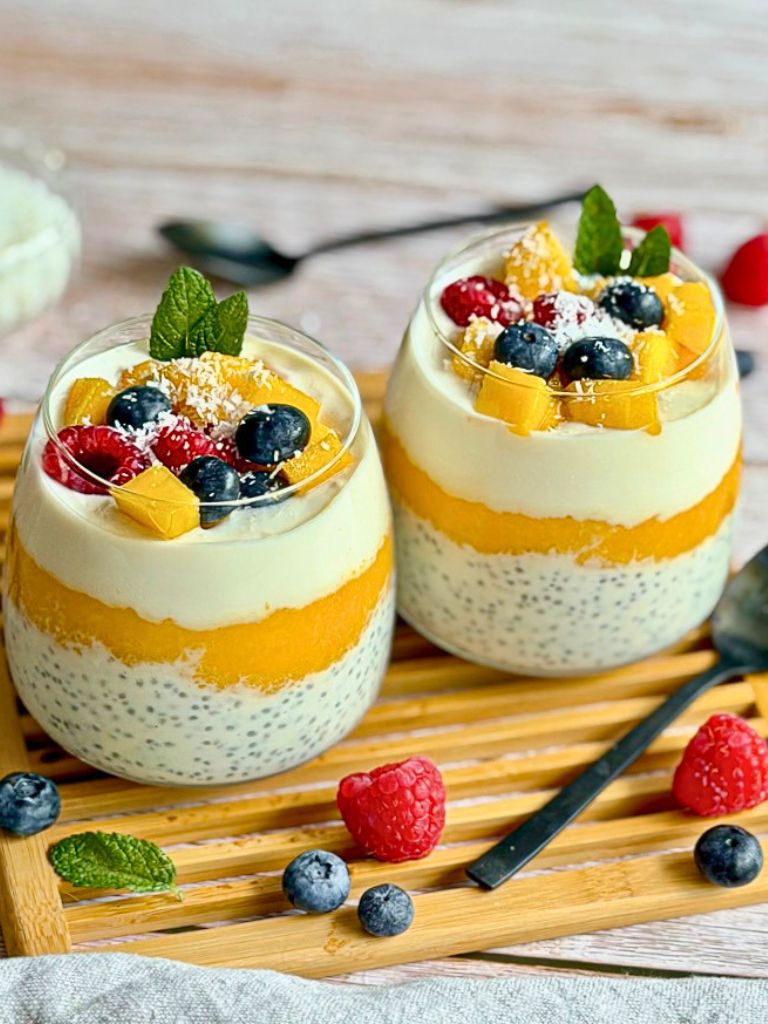 Mango-Chiapudding mit Kokos im Glas auf einem Holztisch.