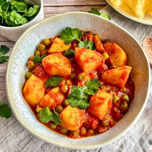 Veganes Aloo Matar: Ein herzhaftes indisches Curry mit Kartoffeln und Erbsen auf einem Teller.