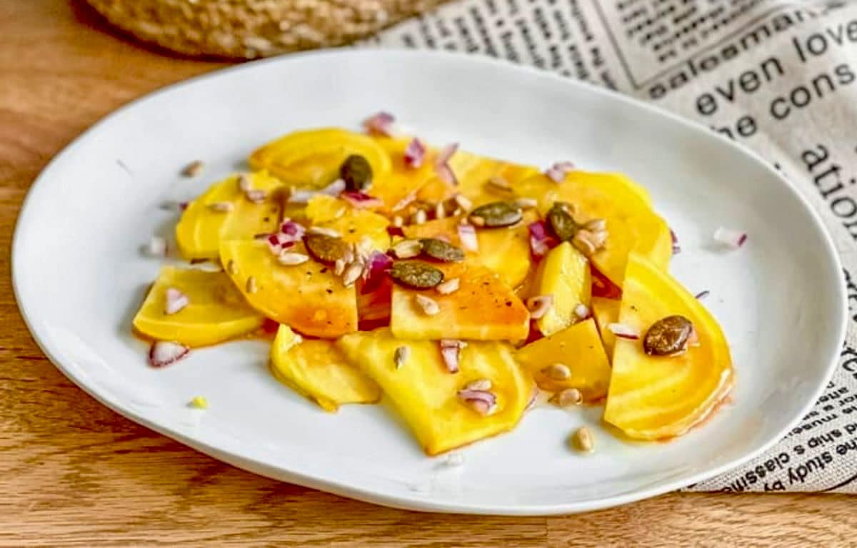 Gelbe-Bete-Salat mit Kerntopping auf einem Teller.