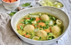 Gemüsesuppe mit veganen Grießklößchen in einem Suppenteller.