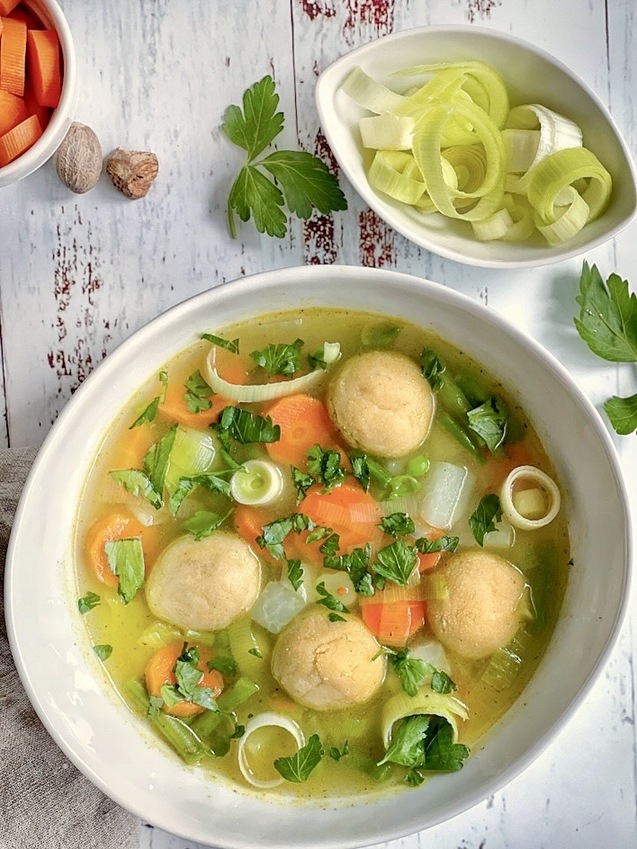 Gemüsesuppe mit veganen Grießklößchen in einem Suppenteller.