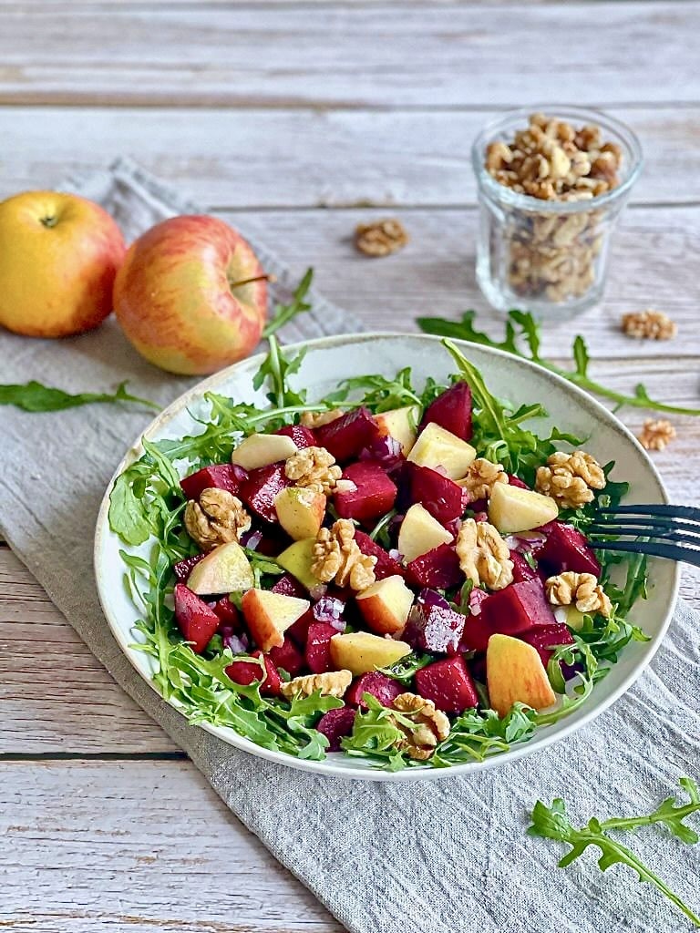 Rote-Bete-Salat mit Apfel, Rucola und Walnüssen auf einem Teller.