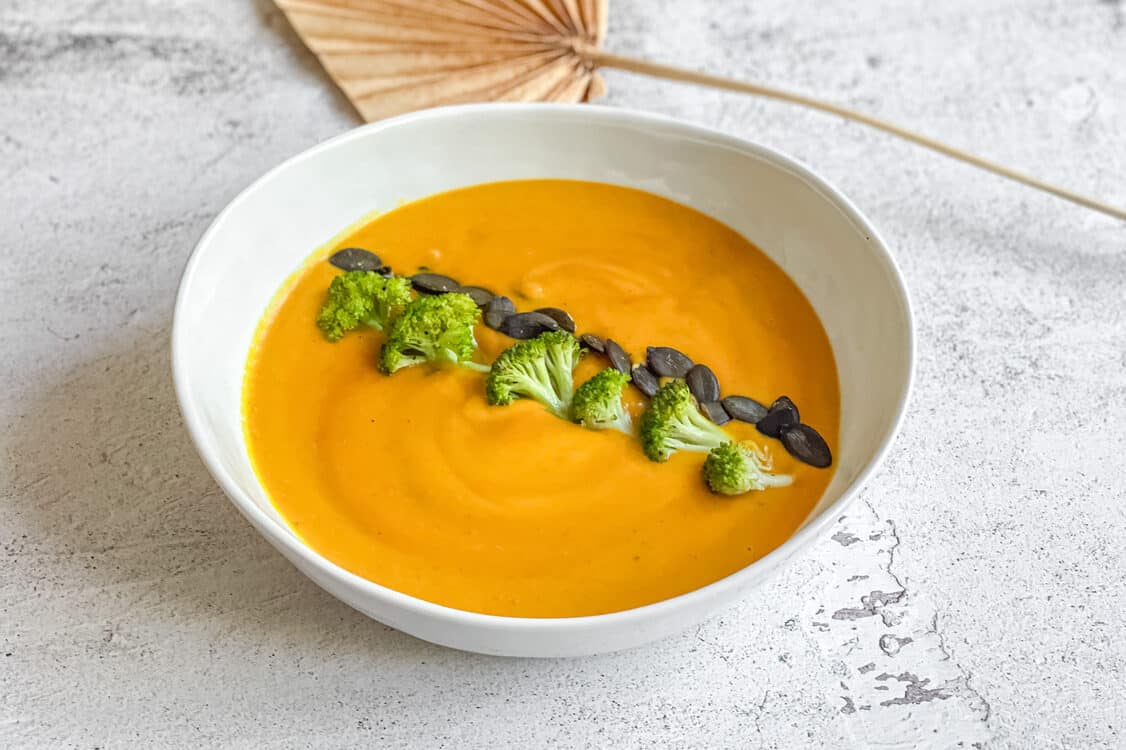 Vegane Kürbissuppe mit Kokosmilch & Brokkoli in einem Suppenteller.