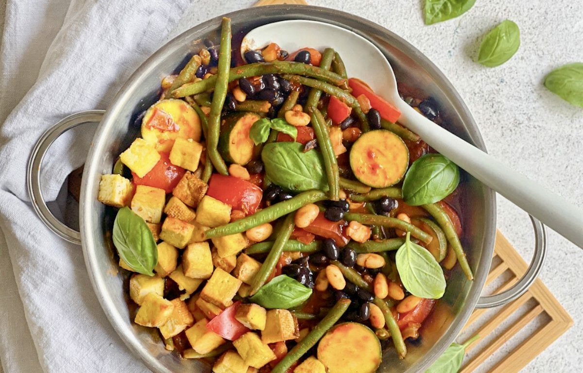 Deftige vegane Bohnenpfanne mit Räuchertofu, Tomaten und Basilikum.