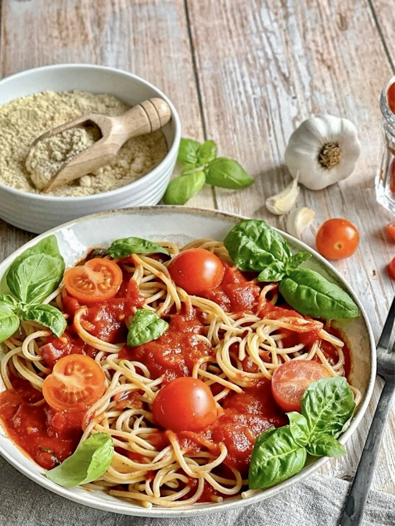 Pasta mit Tomatensoße und Basilikum auf einem Teller.