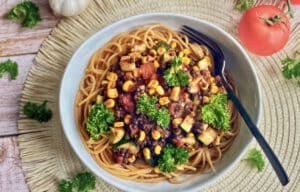 Vegane Beluga-Bolognese mit Gemüse und Spaghetti auf einem Teller.