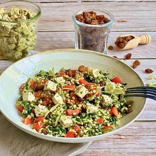 Vegane Bulgurpfanne mit Spinat, Paprika, Rosinen und Kräutertofu auf einem Teller platziert.
