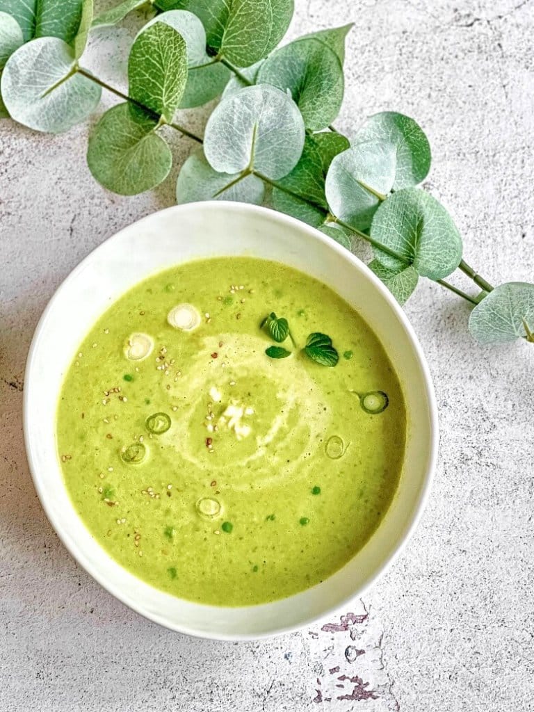 Erbsensuppe mit Kokosmilch, Minze, Sesam und Lauchzwiebeln in einem Suppenteller.