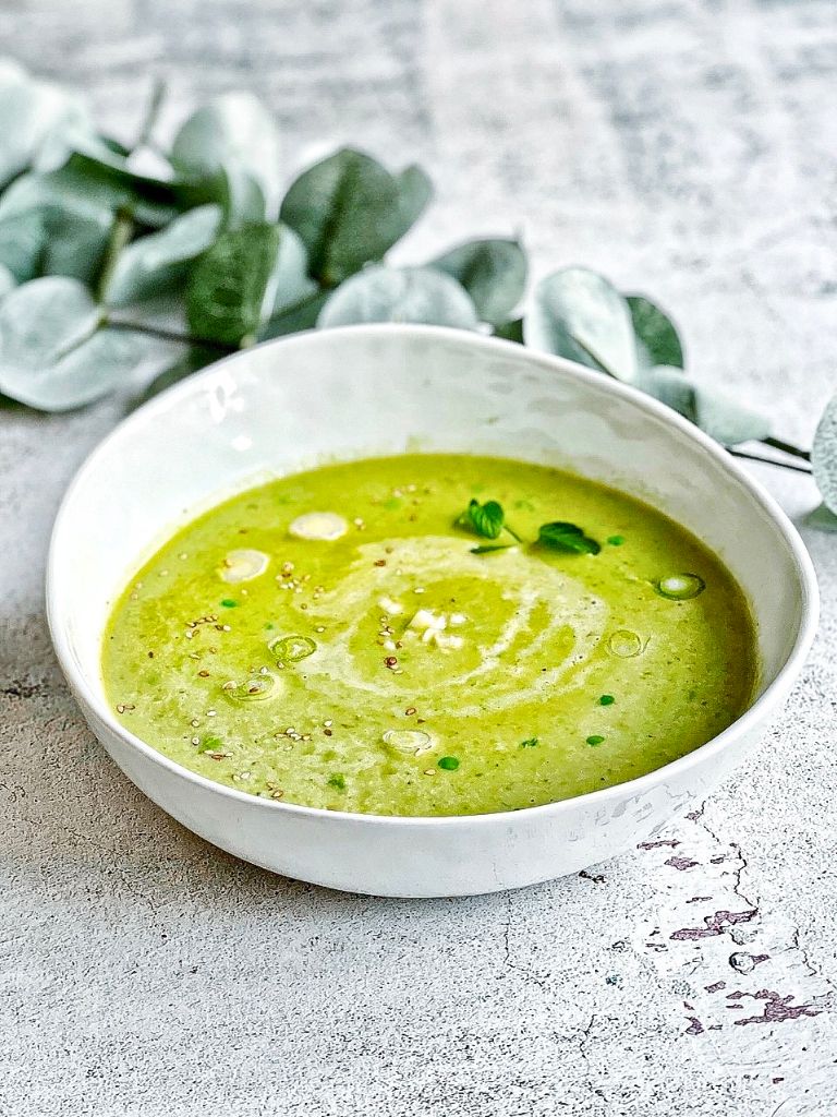 Erbsensuppe mit Kokosmilch, Minze, Sesam und Lauchzwiebeln in einem Suppenteller.