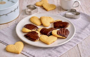 Ingwer-Zitronen-Kekse, teilweise mit Schokoladentopping, auf einem Teller.