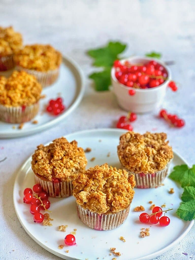 Vegane Johannisbeermuffins mit Streuseln auf Tellern.