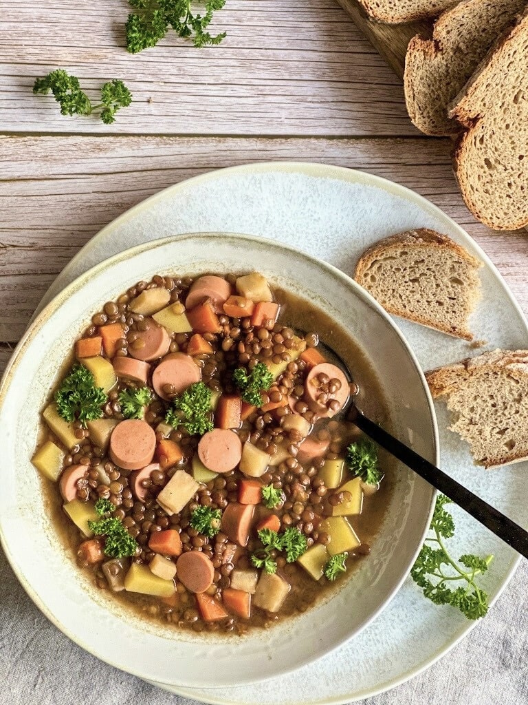 Vegane Linsensuppe mit Würstchen in einem Suppenteller.