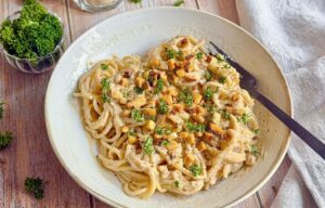 Vegane Spaghetti Carbonara mit Petersilie auf einem Teller.