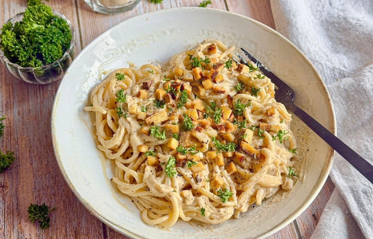 Vegane Spaghetti Carbonara mit Petersilie auf einem Teller.