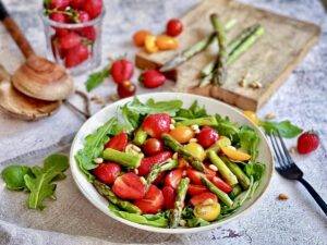 Gesunder und leckerer Spargelsalat mit Erdbeeren & Rucola auf einem Teller.