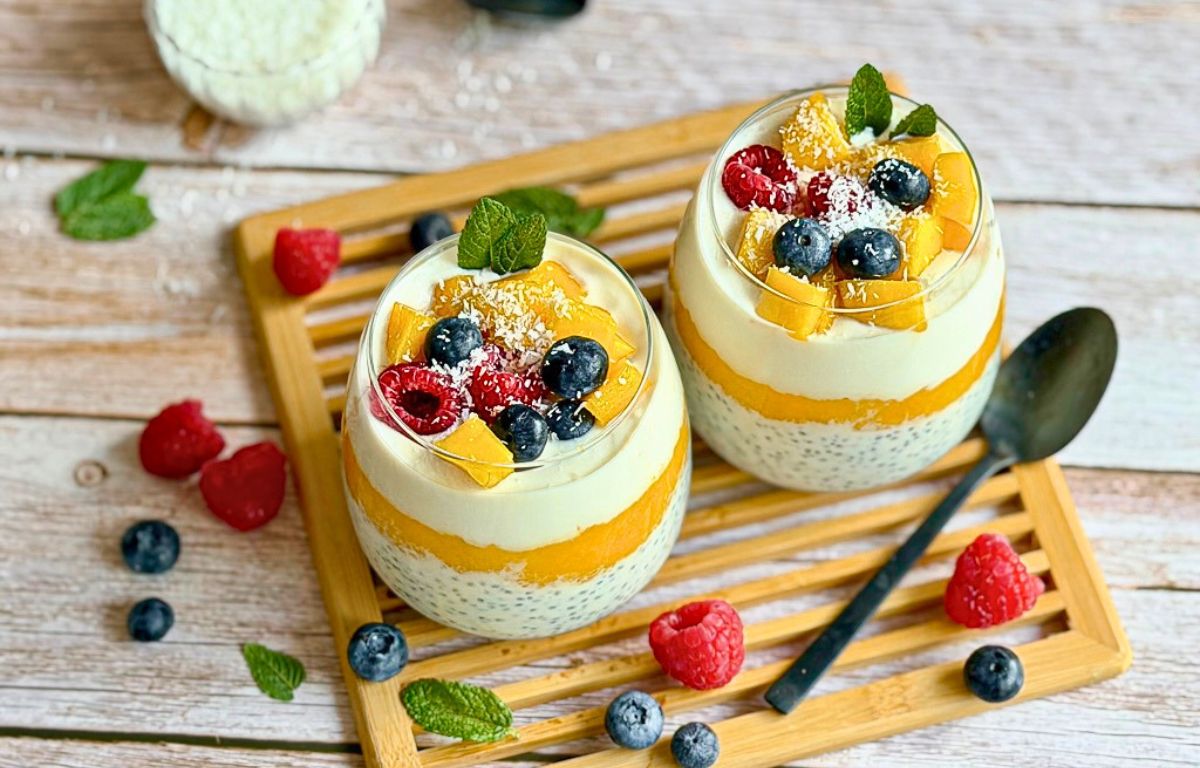 Mango-Chiapudding mit Kokos im Glas auf einem Holztisch.
