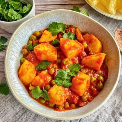 Aloo Matar: Ein herzhaftes indisches Curry mit Kartoffeln und Erbsen auf einem Teller mit Naan-Brot.