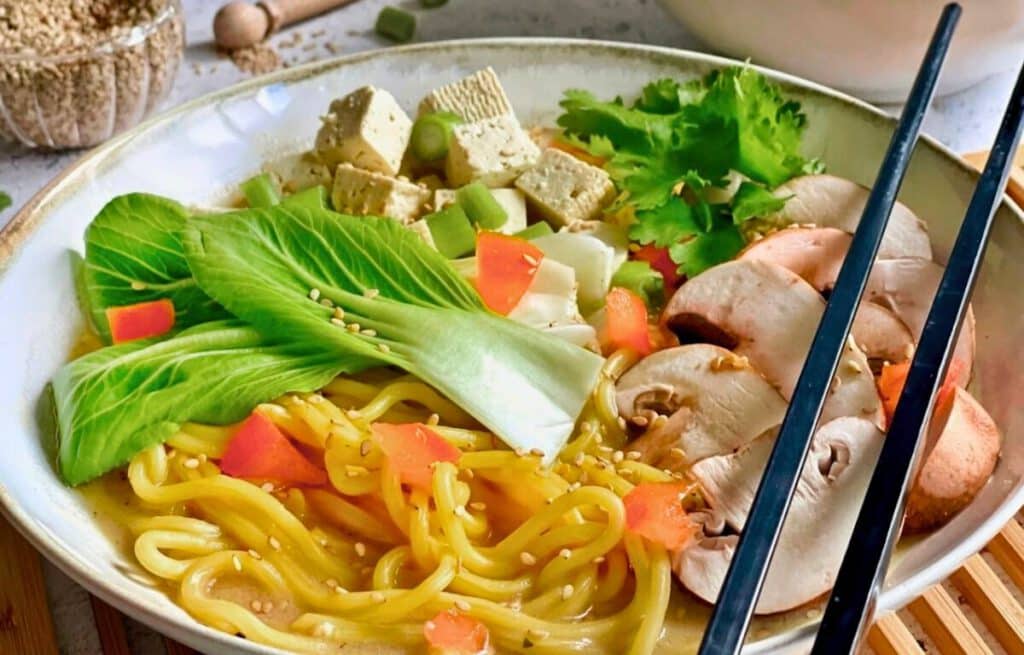 Leckere vegane Misosuppe auf einem Teller mit Stäbchen.