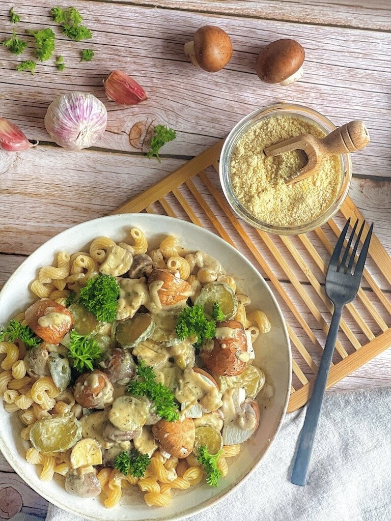 Vegane Nudeln mit Champignons und Gurken auf einem Teller.