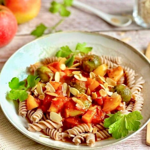 Vegane Pasta mit Rosenkohl in Tomaten-Apfel-Soße auf einem Teller.