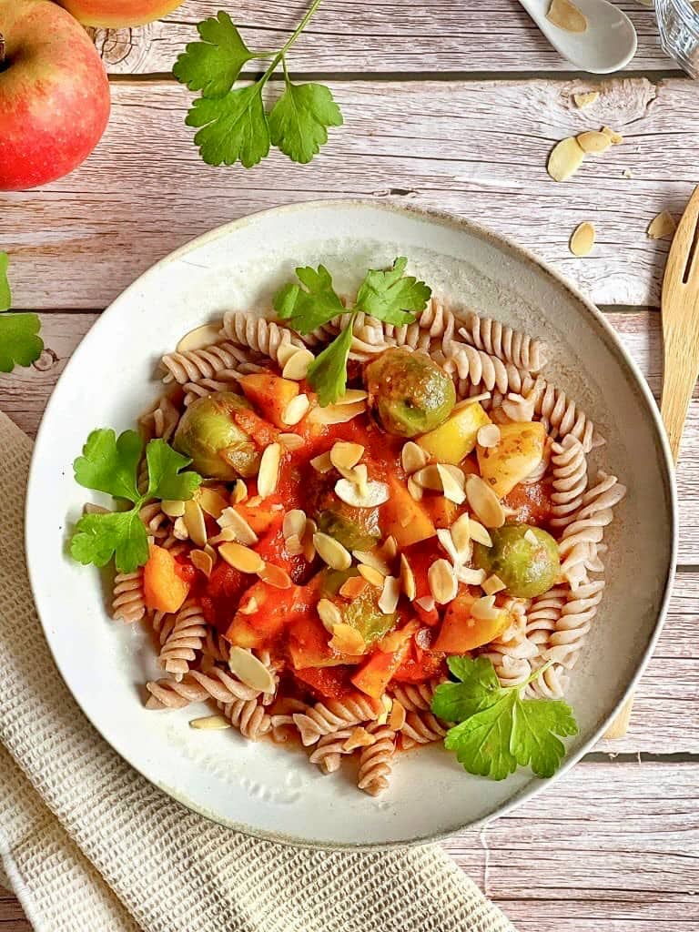 Vegane Pasta mit Rosenkohl in Tomaten-Apfel-Soße auf einem Teller.