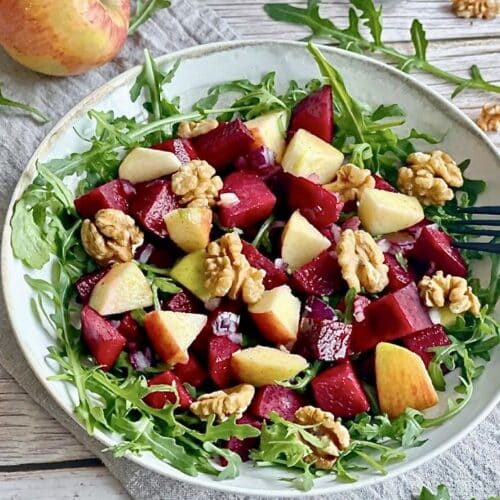 Rote-Bete-Salat mit Apfel, Rucola und Walnüssen auf einem Teller.
