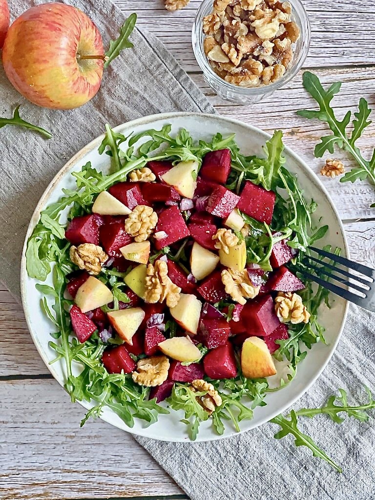 Rote-Bete-Salat mit Apfel, Rucola und Walnüssen auf einem Teller.