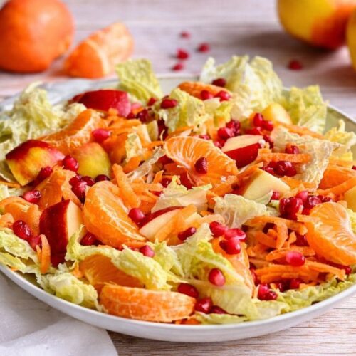 Chinakohlsalat mit Mandarinen, Äpfeln, Karotten und Granatapfelkernen in einer Schüssel