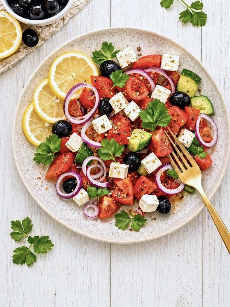 Griechischer Salat mit veganem Feta auf einem Teller.