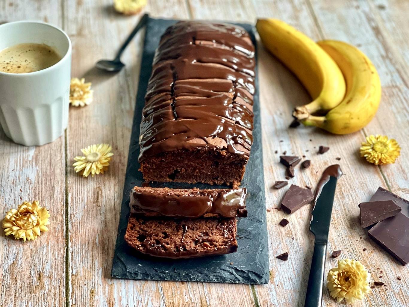 Schoko-Bananenbrot auf einer Schieferplatte mit einer Tasse Kaffee.