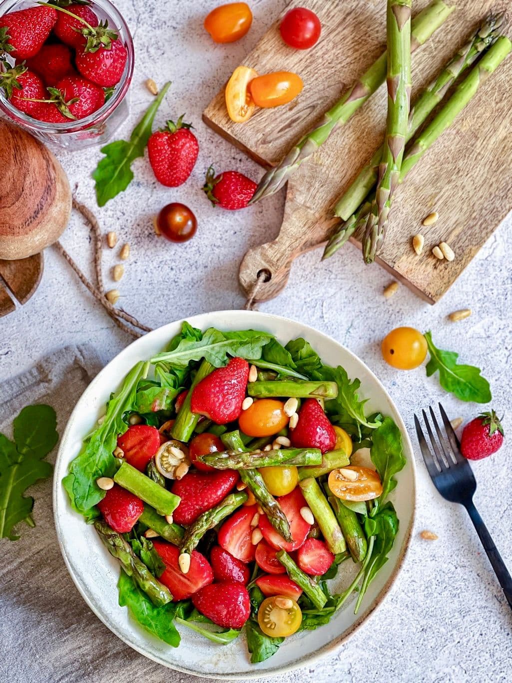Einfacher Spargelsalat mit Erdbeeren und Rucola auf einem Teller.